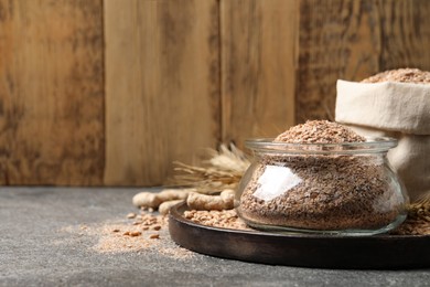 Photo of Jar of wheat bran on grey table, space for text