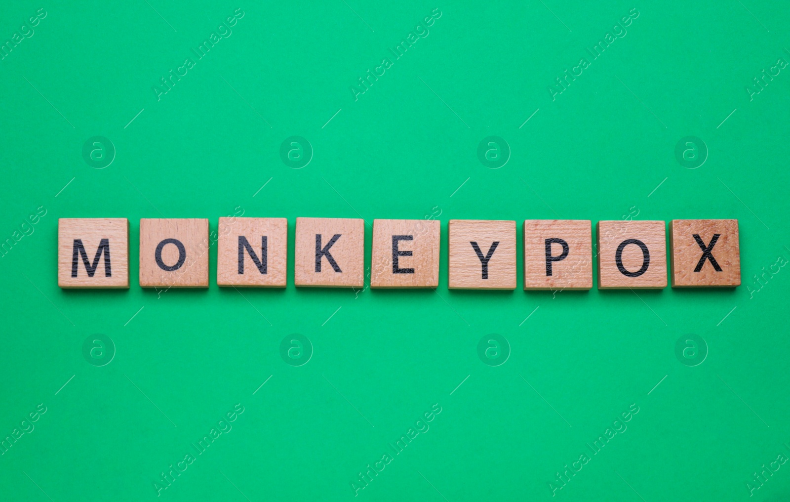 Photo of Word Monkeypox made of wooden squares on green background, top view