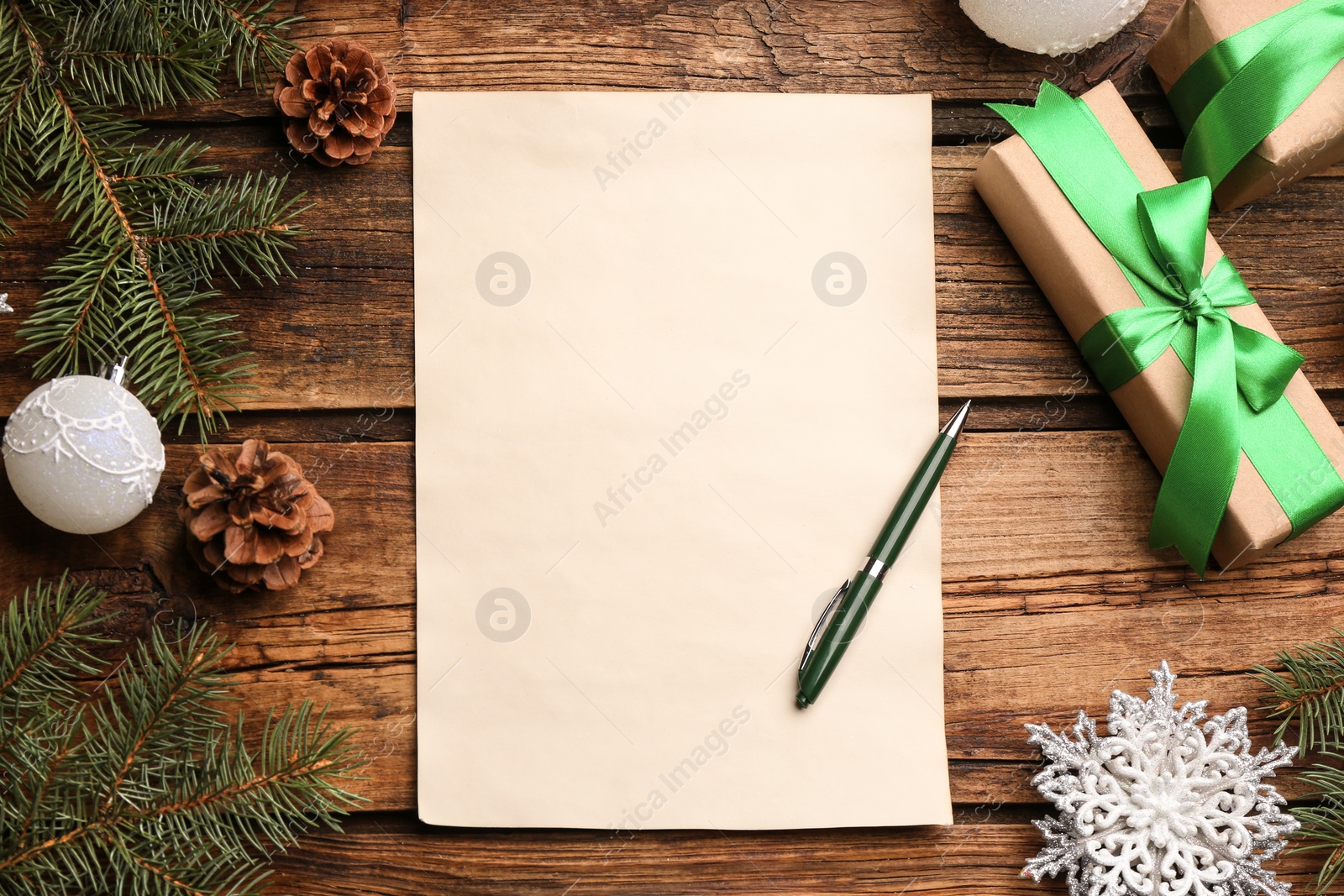 Photo of Flat lay composition with blank sheet of paper on wooden table, space for text. Writing letter to Santa