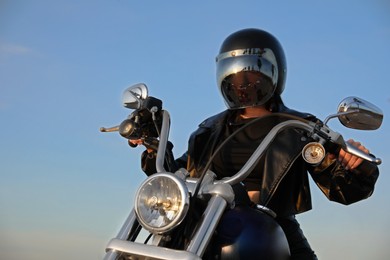 Young woman in helmet riding motorcycle on sunny day