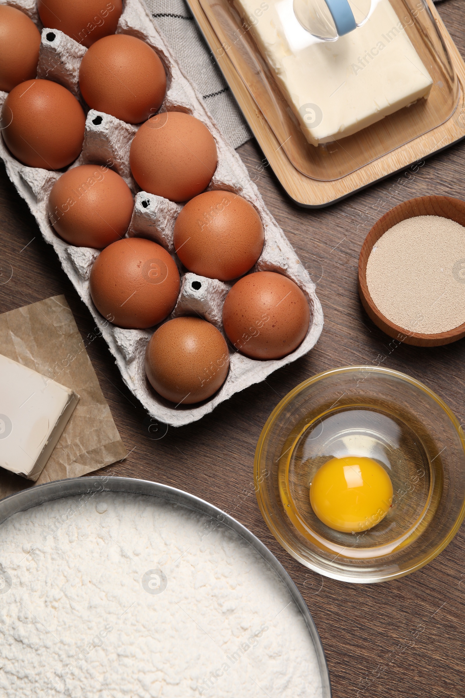 Photo of Flat lay composition with flour, eggs and ingredients on wooden table. Cooking yeast cake