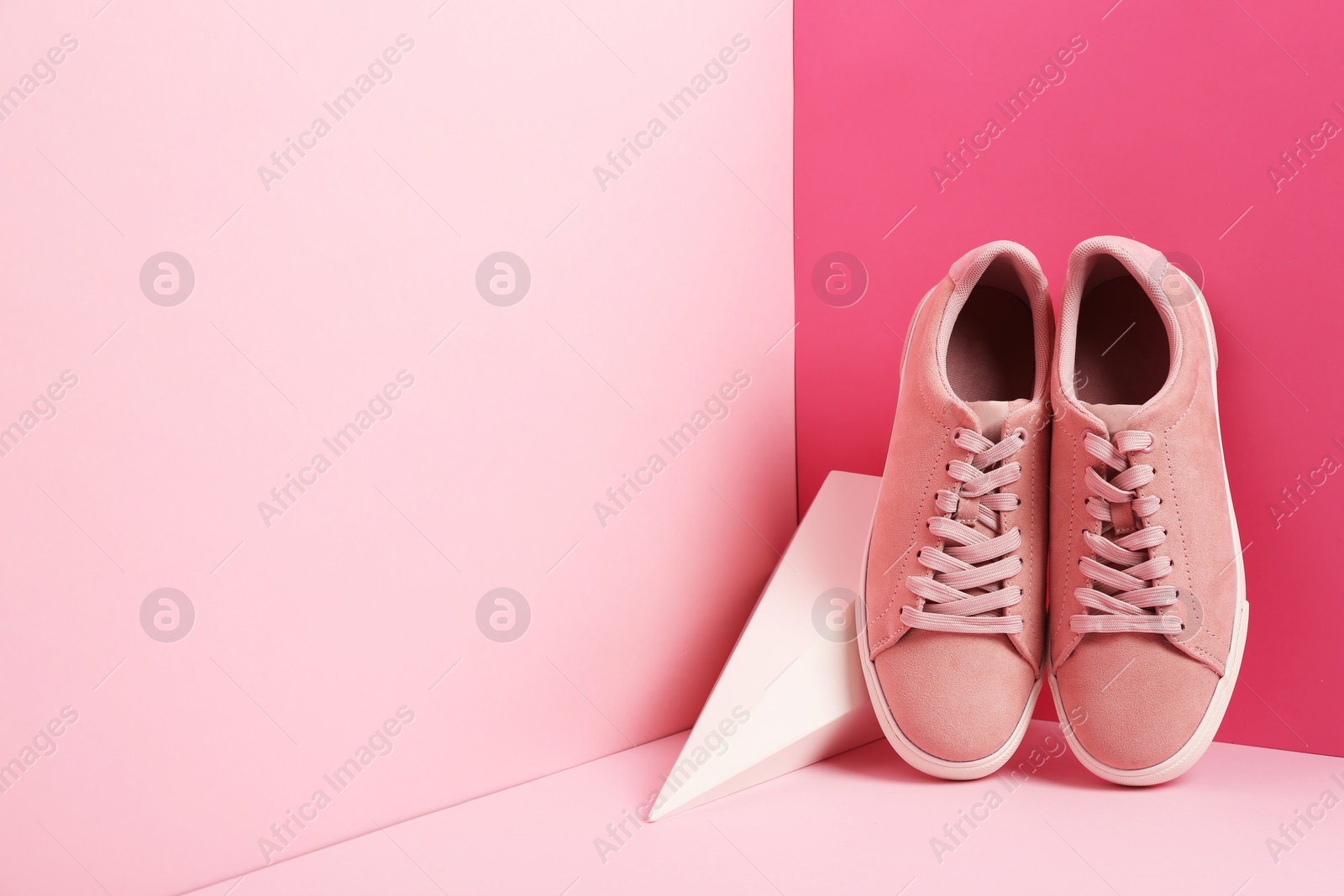 Photo of Comfortable sneakers and pyramid on color background, space for text