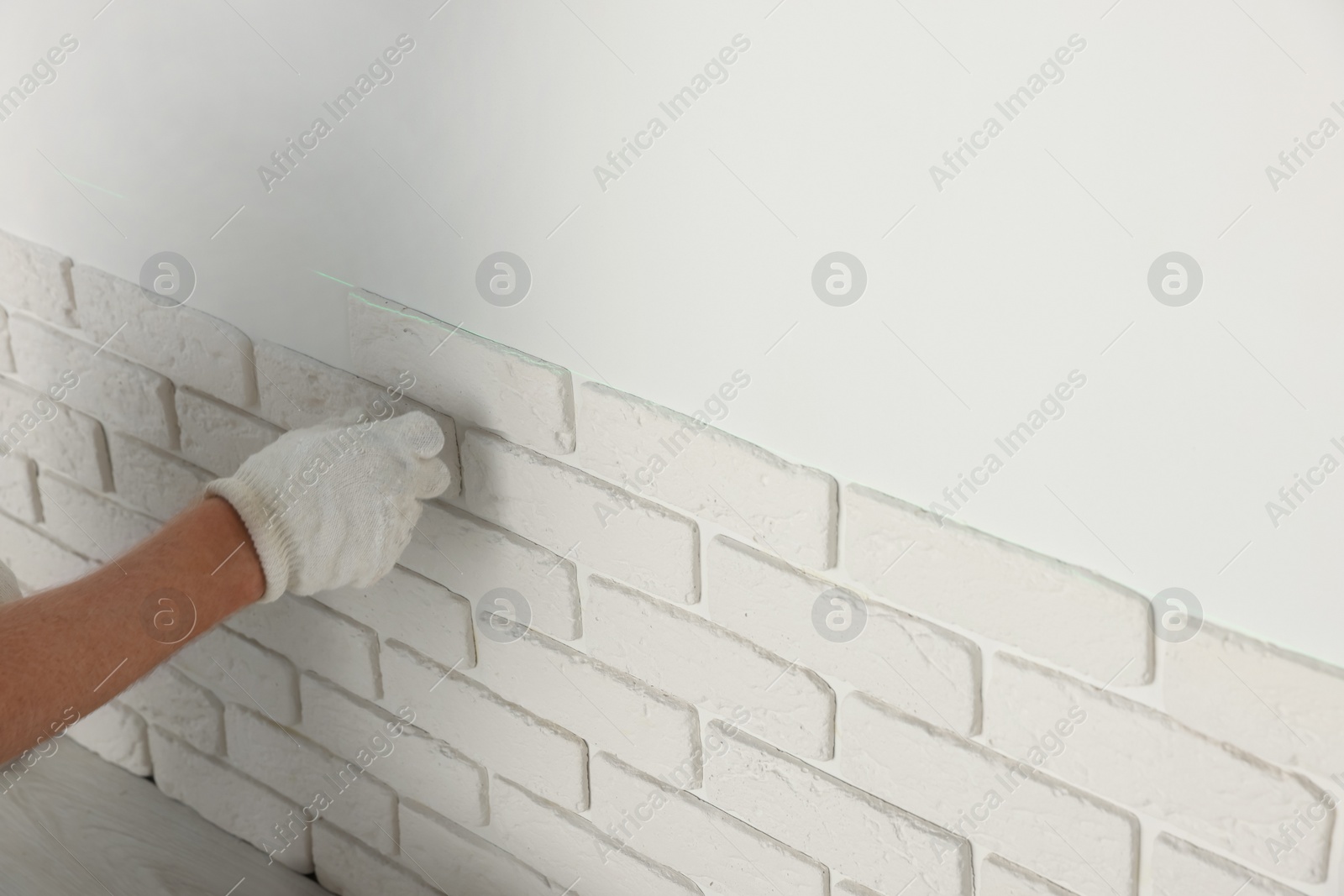 Photo of Worker installing decorative wall tiles in room, closeup