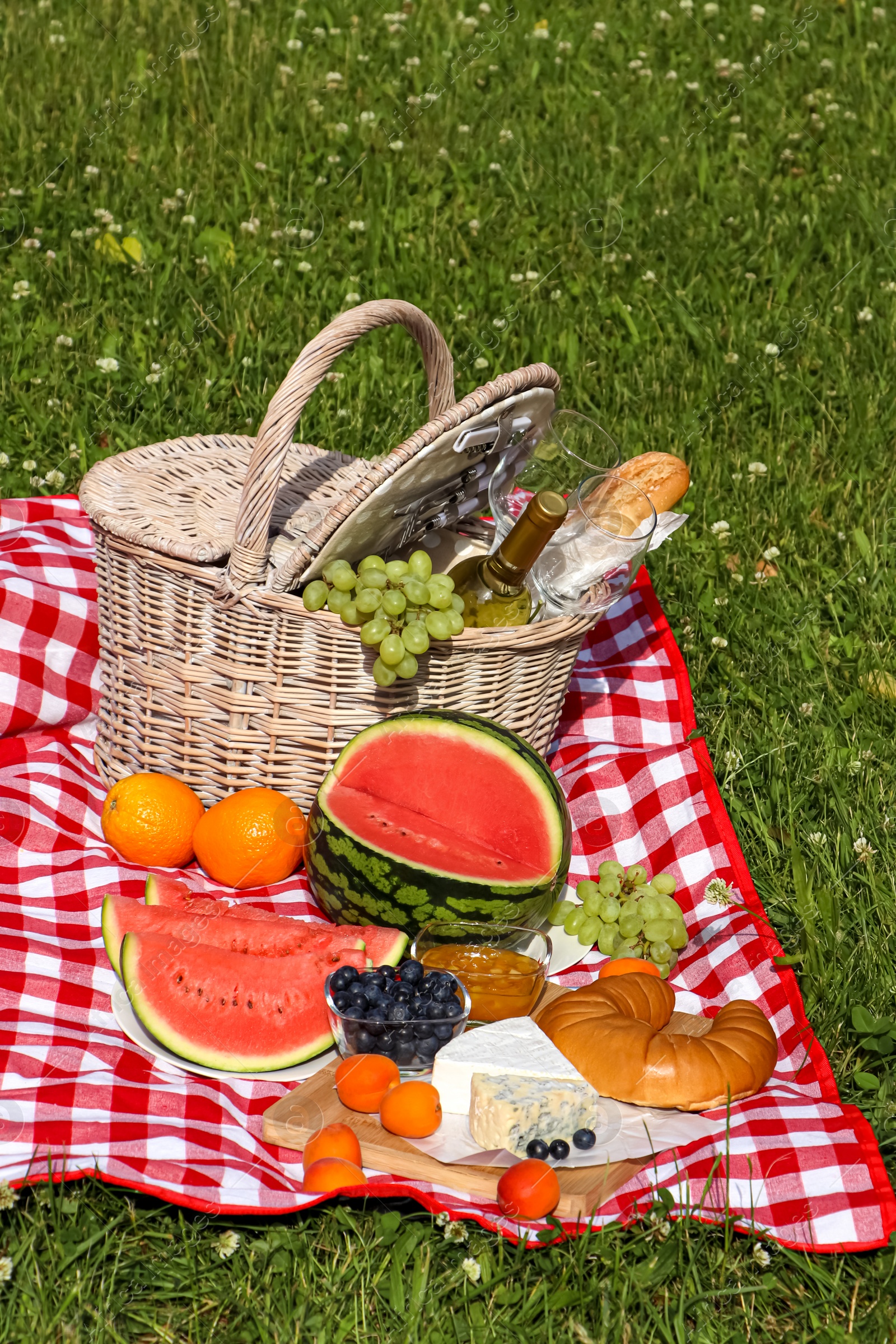 Photo of Picnic blanket with delicious food and wine outdoors on summer day