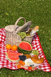 Photo of Picnic blanket with delicious food and wine outdoors on summer day