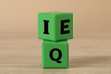 Photo of Green cubes with letters E, I and Q on wooden table