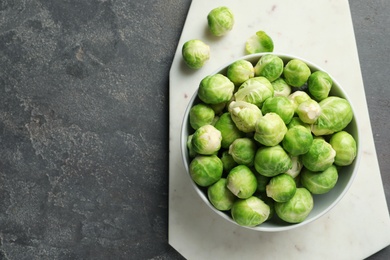 Board with bowl of Brussels sprouts on grey background, top view. Space for text