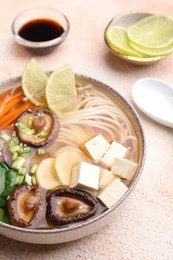 Photo of Bowl of vegetarian ramen served on color textured table, closeup