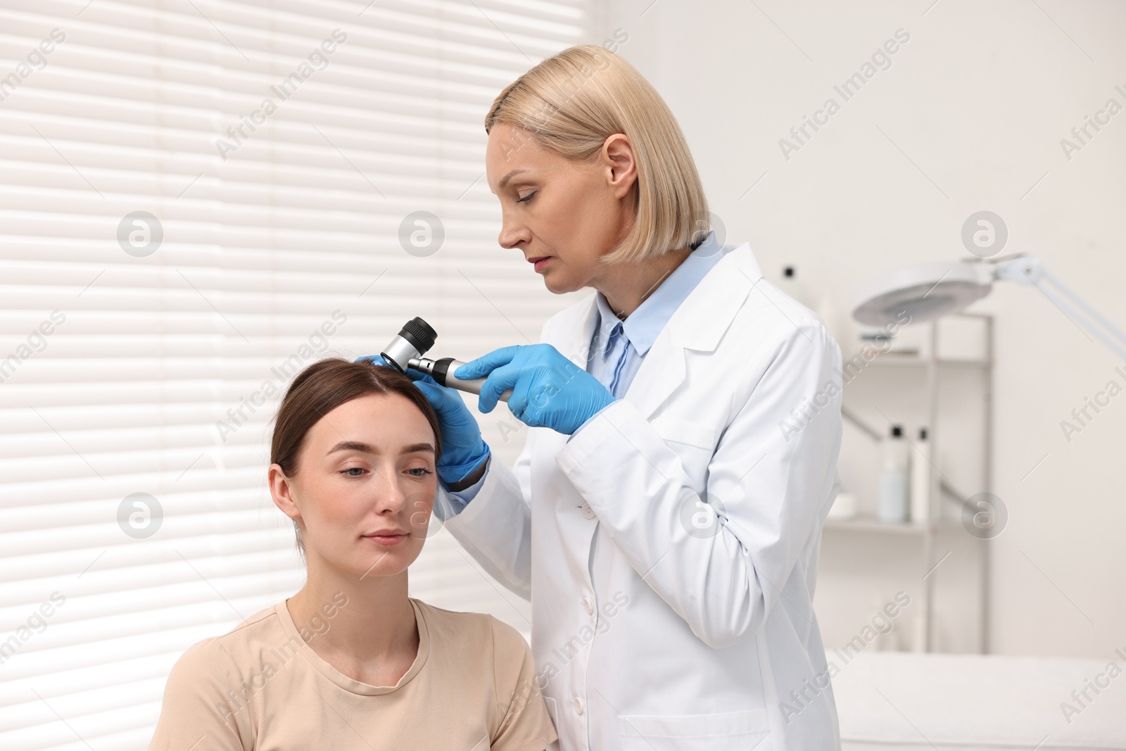 Photo of Trichologist with dermatoscope examining patient`s hair in clinic