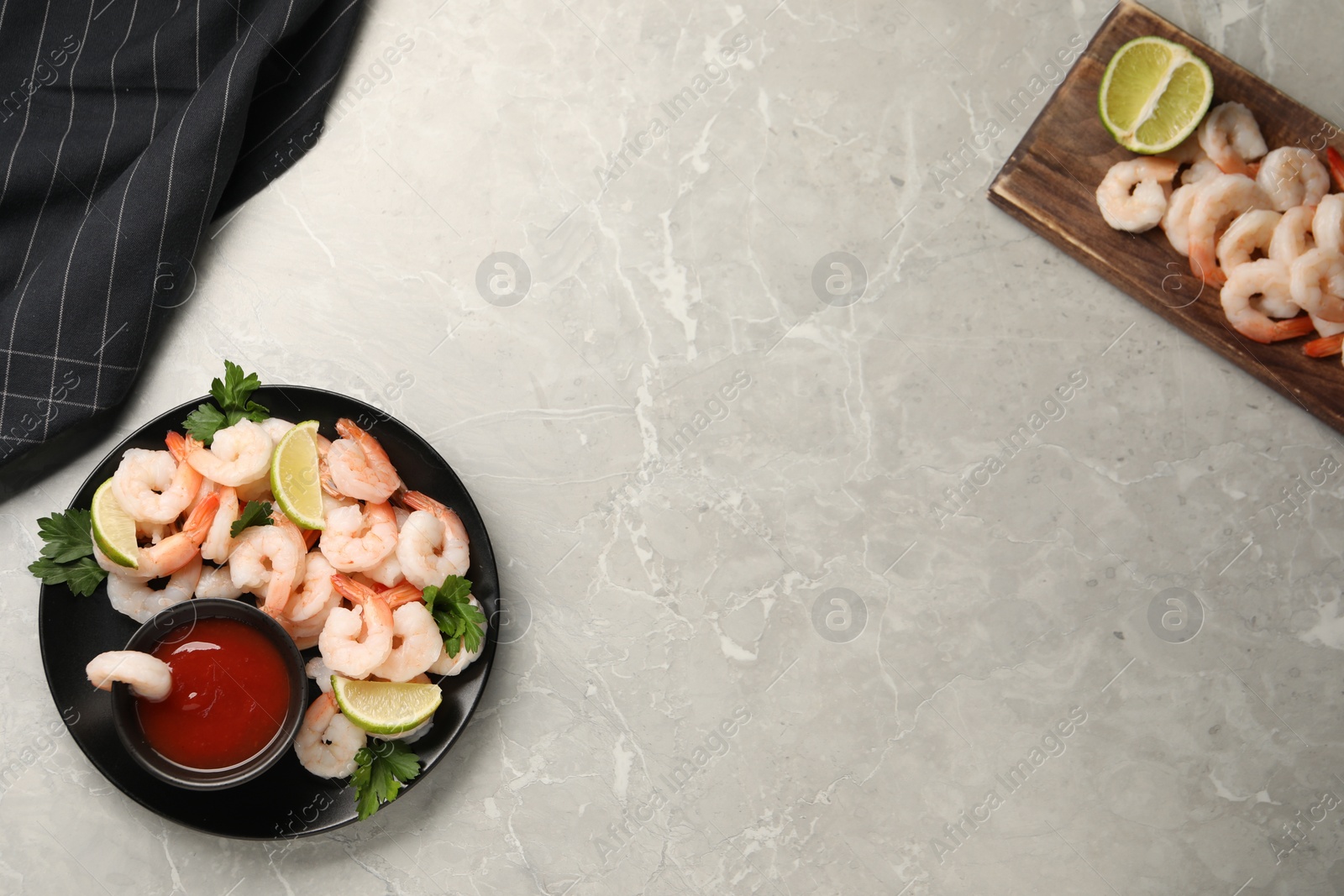 Photo of Tasty boiled shrimps with cocktail sauce, parsley and lime on light grey table, flat lay. Space for text