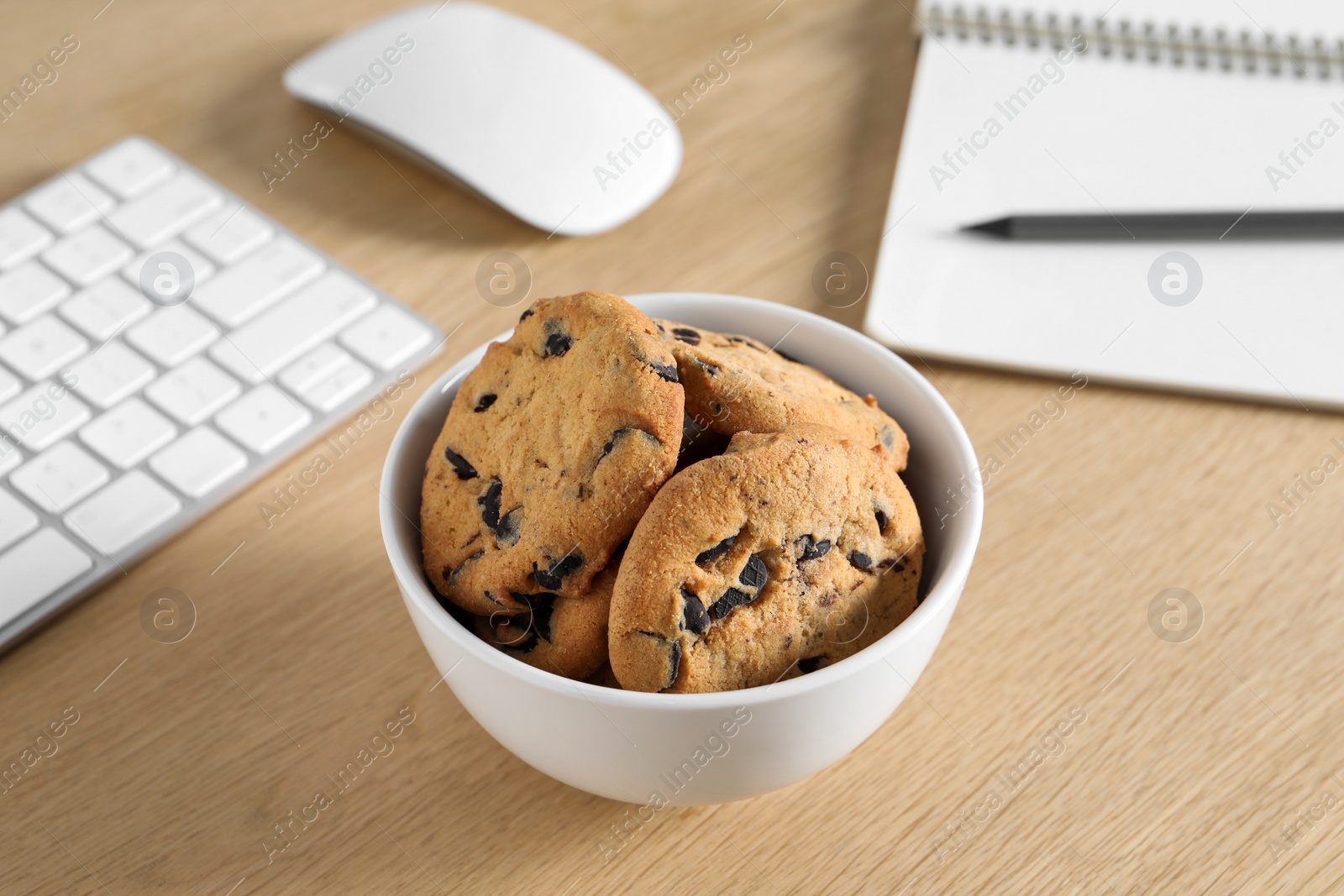 Photo of Chocolate chip cookies on wooden table at workplace