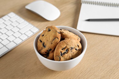 Photo of Chocolate chip cookies on wooden table at workplace