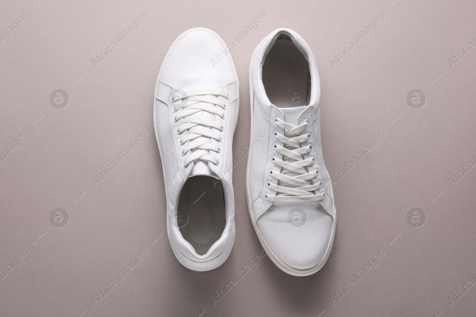 Photo of Pair of stylish white sneakers on grey background, top view