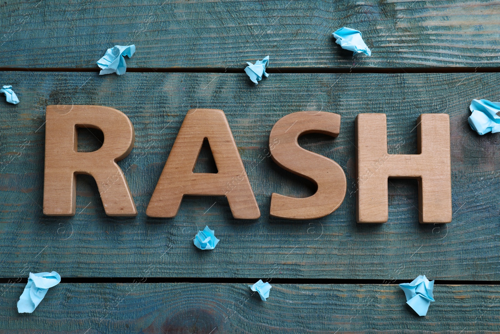 Photo of Word Rash made of wooden letters and crumpled paper on light blue table, flat lay