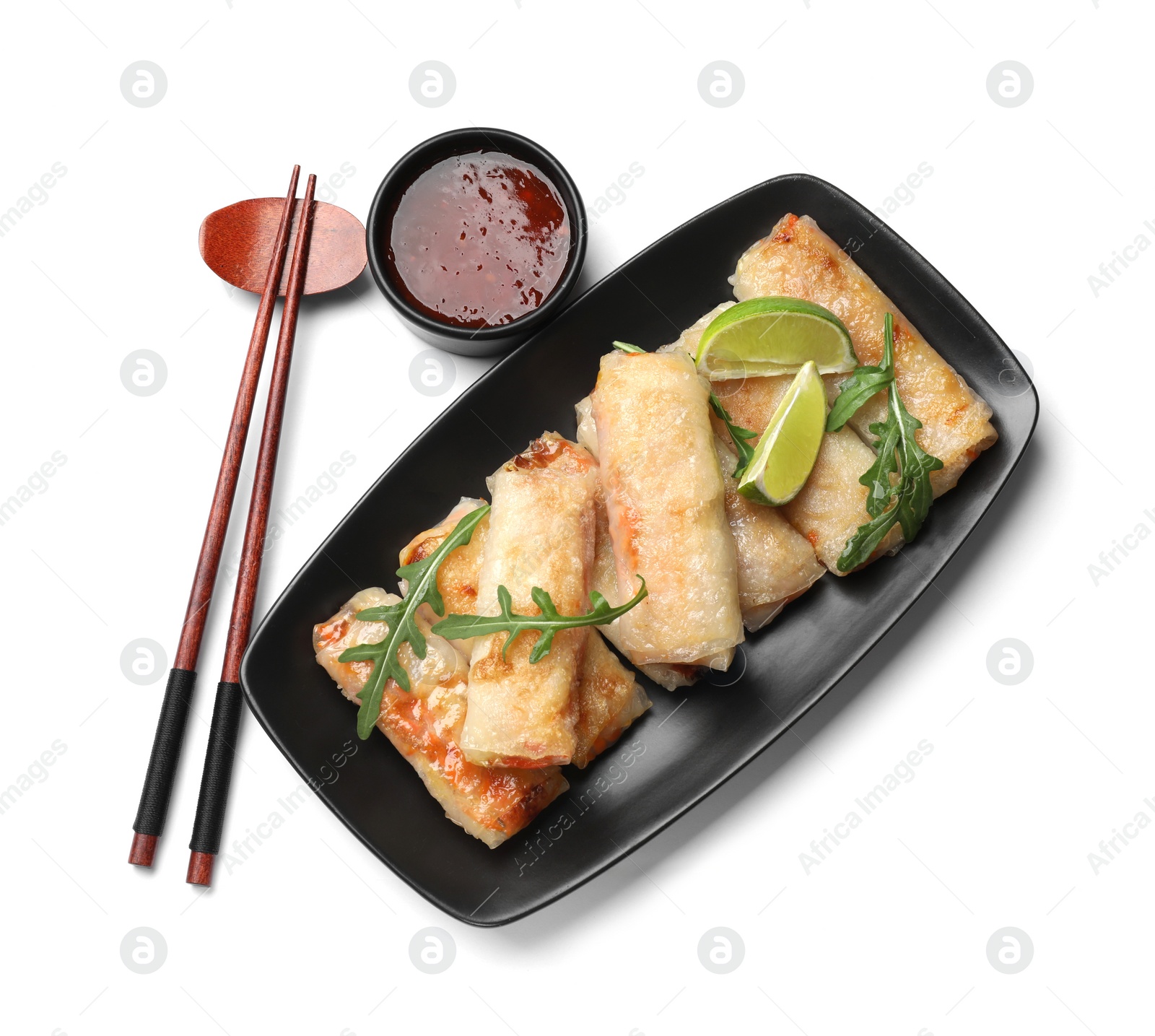 Photo of Tasty fried spring rolls, arugula, lime, chopsticks and sauce isolated on white, top view