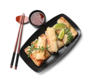 Tasty fried spring rolls, arugula, lime, chopsticks and sauce isolated on white, top view