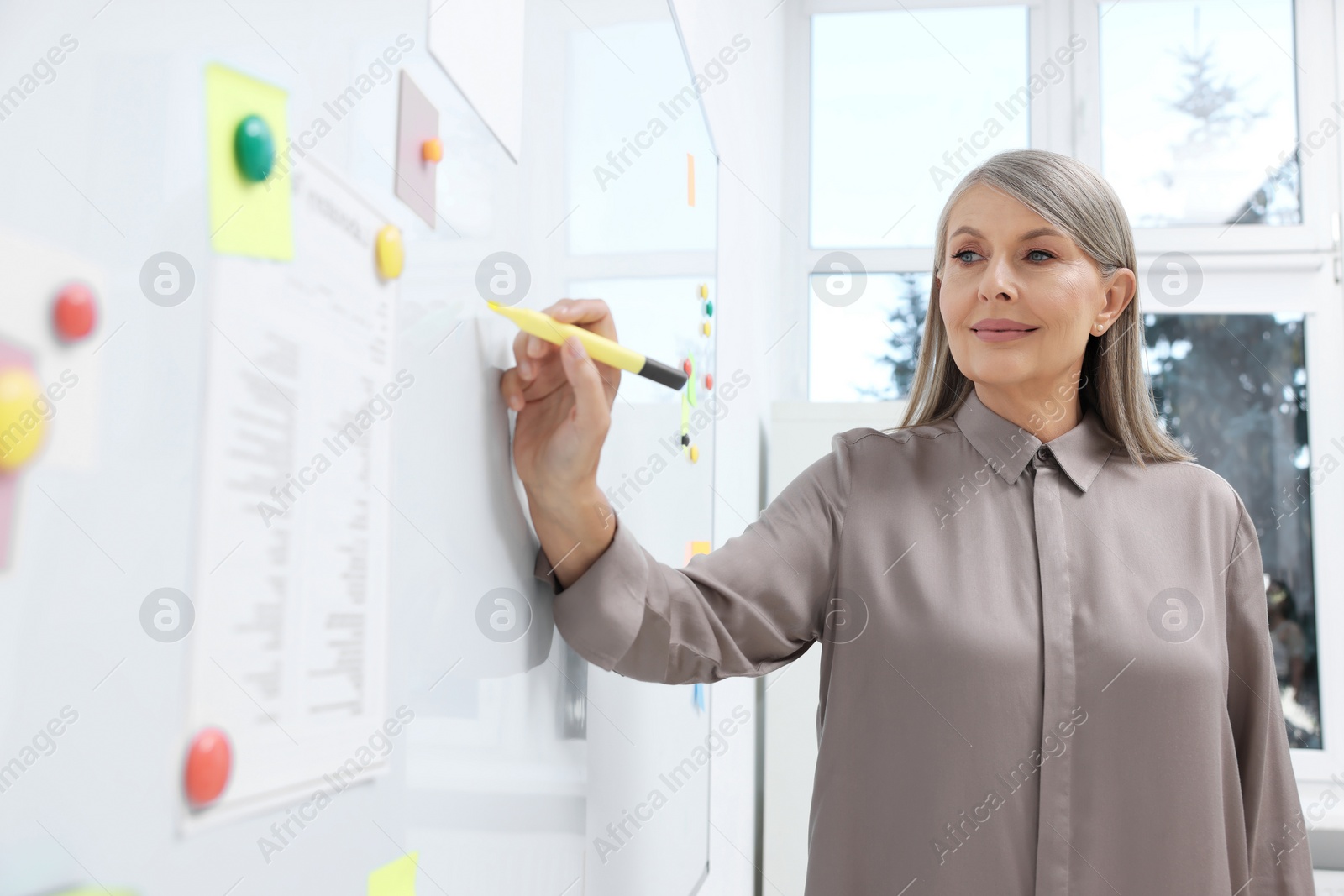 Photo of Professor explaining something with marker at whiteboard in classroom