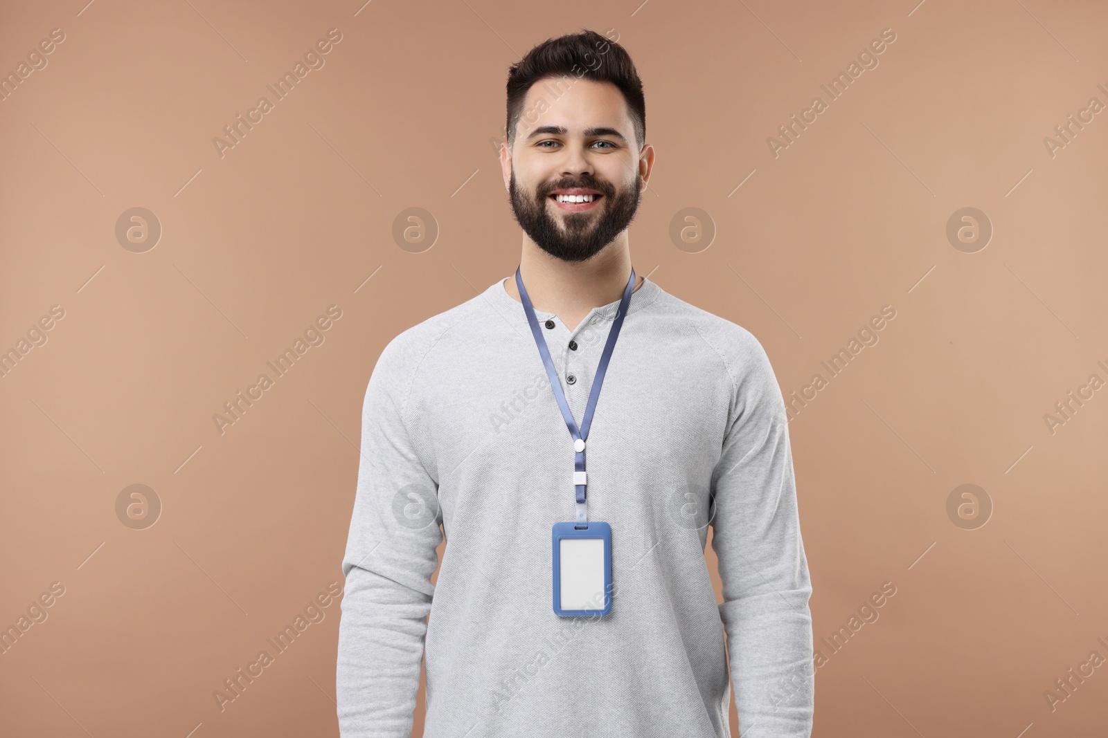 Photo of Happy young man with blank badge on beige background