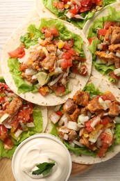 Photo of Delicious tacos with vegetables, meat and sauce on white wooden table, top view