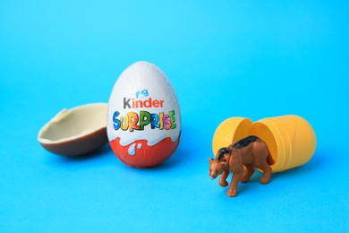 Photo of Slynchev Bryag, Bulgaria - May 25, 2023: Kinder Surprise Eggs, plastic capsule and toy on light blue background