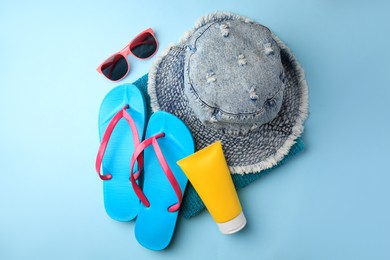Photo of Flat lay composition with sunscreen and different beach accessories on light blue background