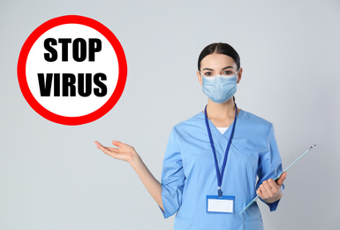 Image of Young doctor in medical mask and sign STOP VIRUS on light background