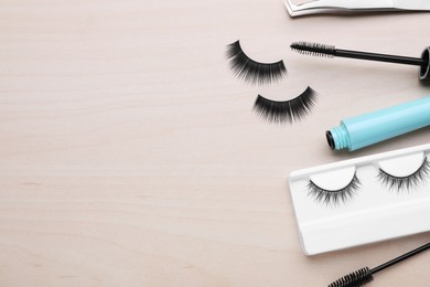 Flat lay composition with false eyelashes and tools on wooden table. Space for text