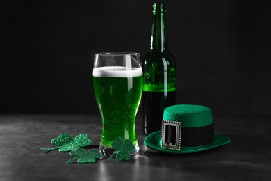 Photo of St. Patrick's day celebration. Green beer, leprechaun hat and decorative clover leaves on grey table