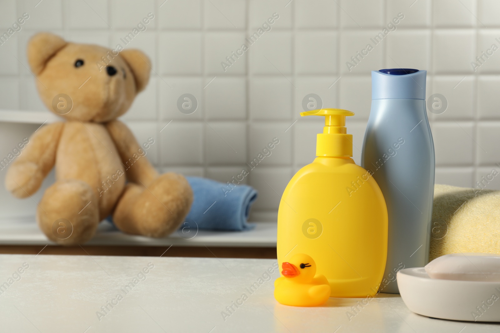 Photo of Baby cosmetic products, bath duck and towel on white table. Space for text