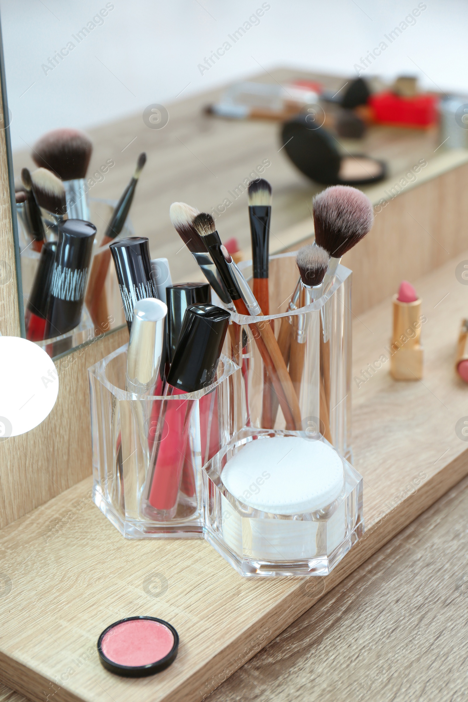 Photo of Organizer with cosmetic products for makeup on table near mirror