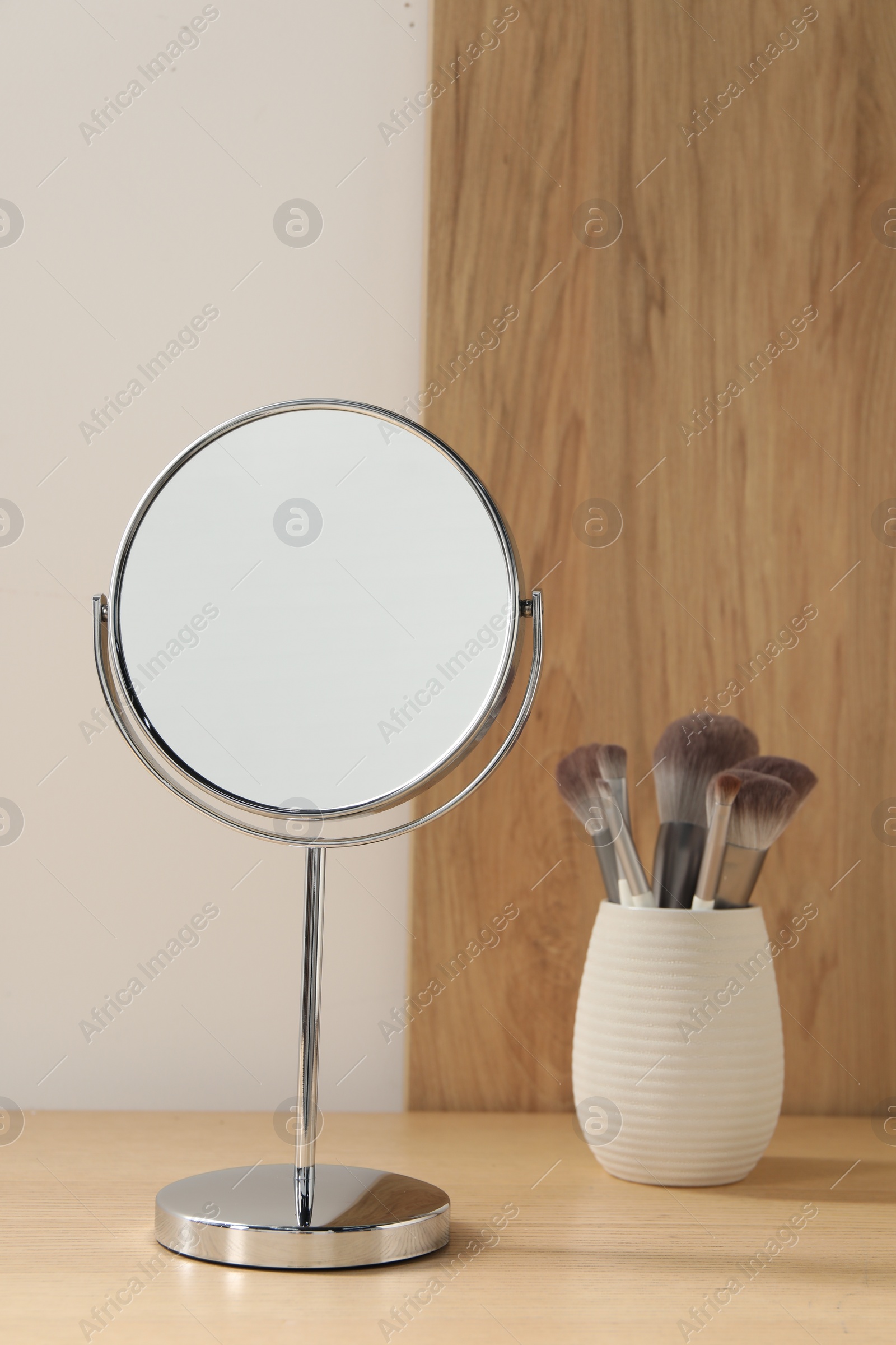 Photo of Mirror and makeup brushes on wooden dressing table in room