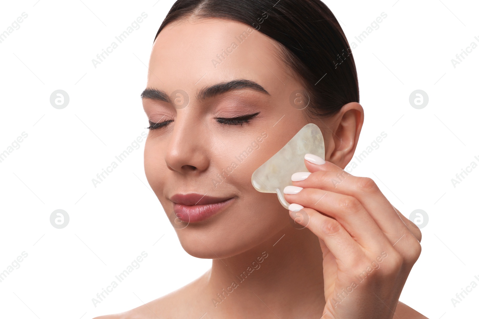 Photo of Beautiful young woman doing facial massage with gua sha tool on white background, closeup