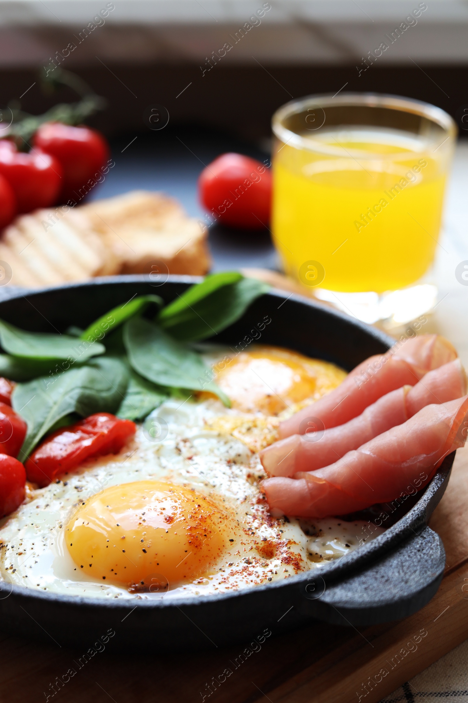 Photo of Delicious fried eggs with spinach, tomatoes and ham served on table