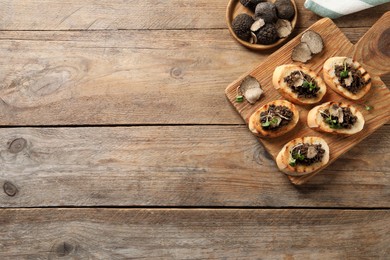 Delicious bruschettas with truffle sauce and microgreens on wooden table, flat lay. Space for text