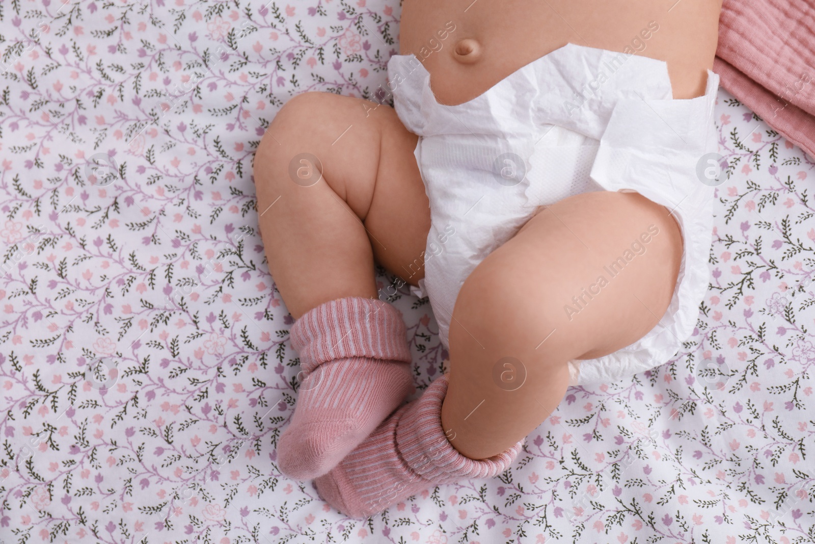 Photo of Little baby in diaper on bed, closeup