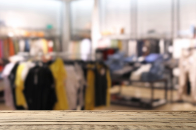 Image of Empty wooden table and blurred view of store with modern clothes