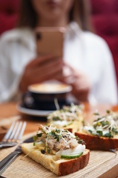 Photo of Food blogger taking photo of lunch in cafe, focus on delicious bruschettas