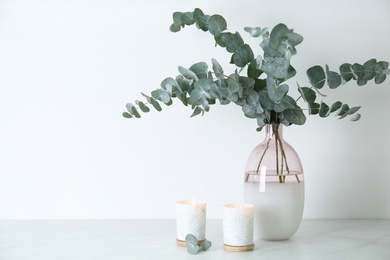 Beautiful eucalyptus branches and burning candles on grey table, space for text. Interior element
