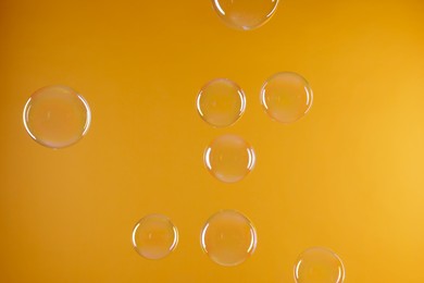 Many beautiful soap bubbles on orange background