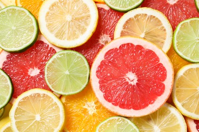 Photo of Different sliced citrus fruits as background, top view