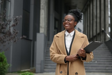 Happy woman with clipboard outdoors, space for text. Lawyer, businesswoman, accountant or manager