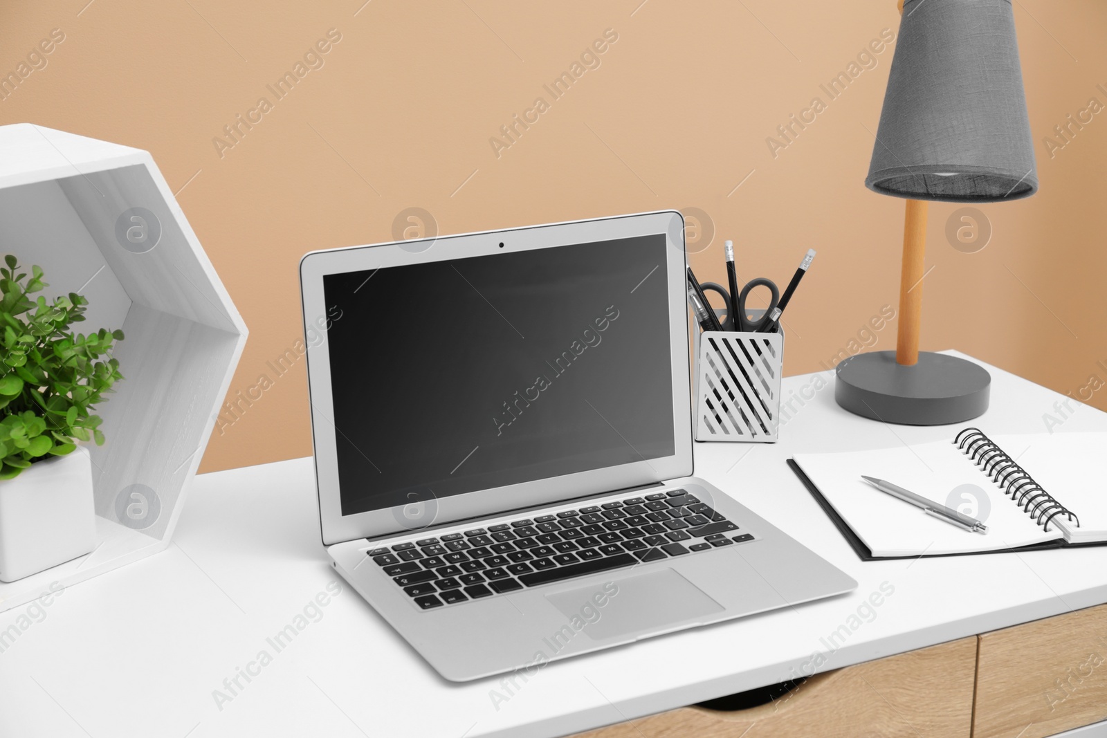 Photo of Cozy workplace with laptop and stationery on desk. Home office