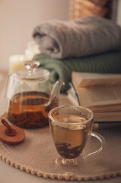 Glass teapot and cup of hot tea on table in room. Cozy home atmosphere