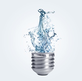 Image of Light bulb with water splashes on light background. Alternative energy source