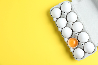 Photo of Fresh chicken eggs in box on yellow background, top view. Space for text