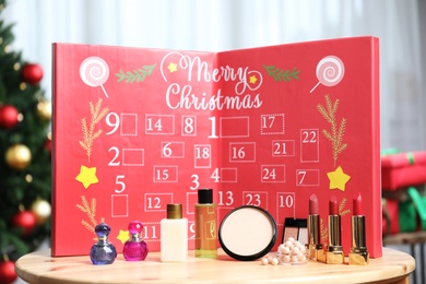 Photo of Christmas advent calendar with perfumes, skin care and decorative cosmetics on table