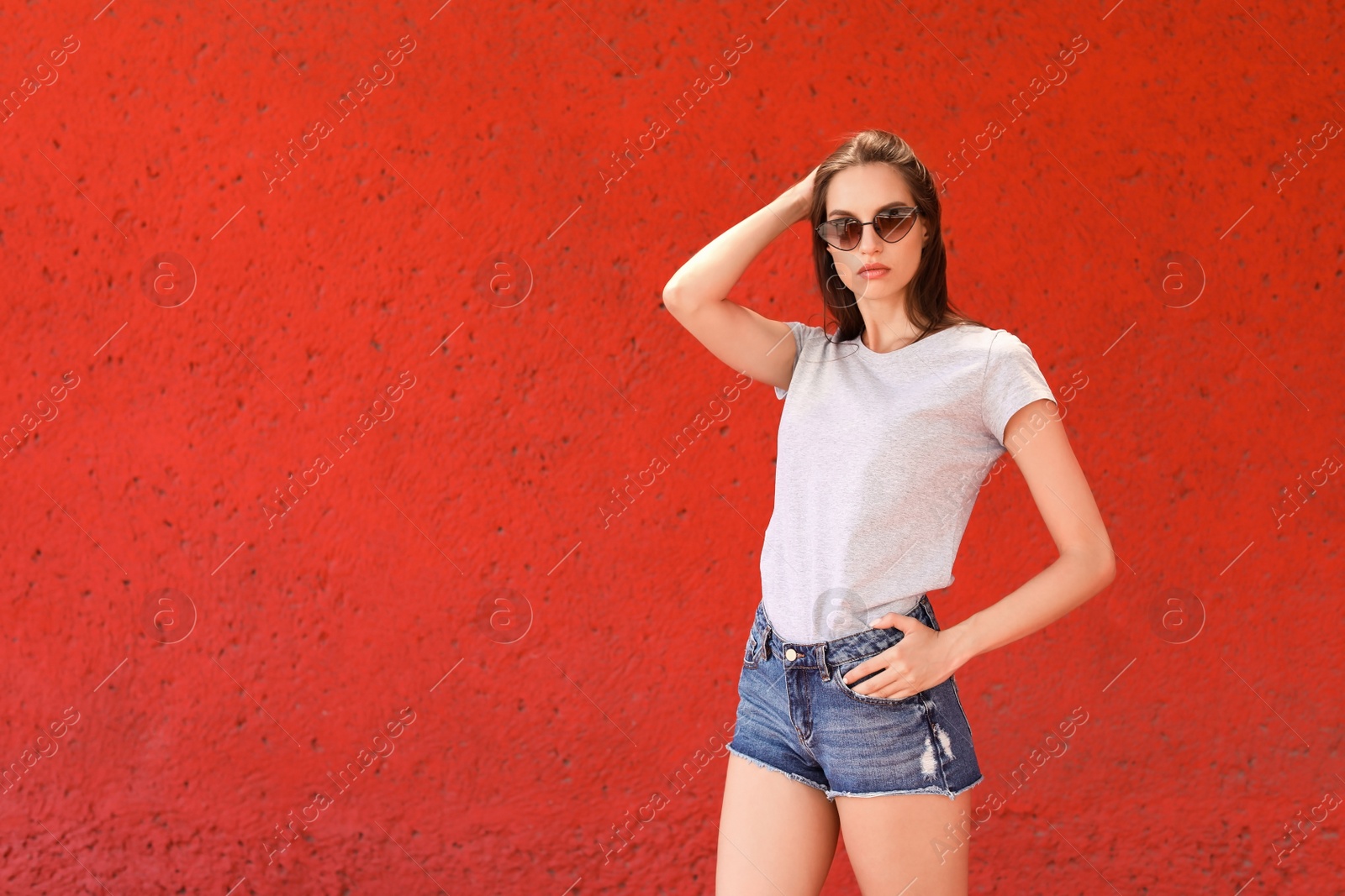 Photo of Young woman wearing gray t-shirt near color wall on street