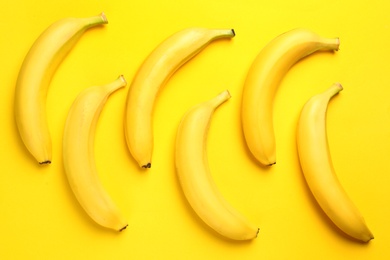 Ripe tasty bananas on yellow background, flat lay