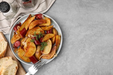 Photo of Delicious baked potato with thin dry smoked sausages served on gray table, flat lay. Space for text