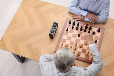 Photo of Men playing chess during tournament at wooden table, above view. Space for text